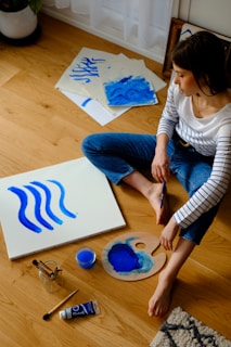 woman in white long sleeve shirt and blue denim jeans sitting on brown wooden table