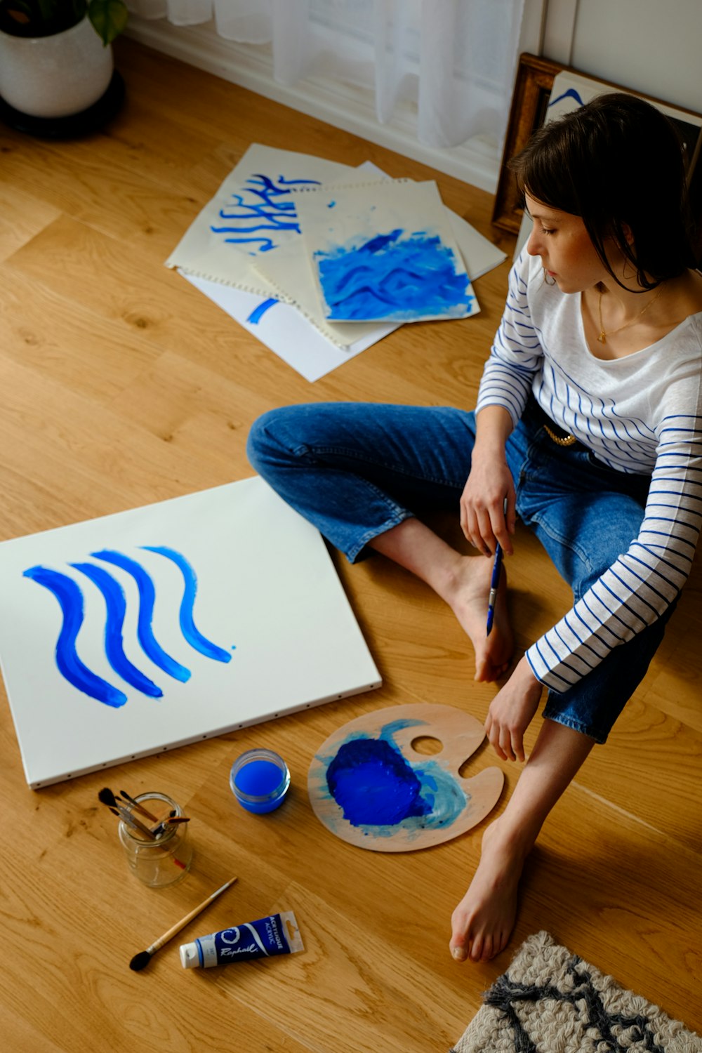 Mujer con camisa blanca de manga larga y jeans de mezclilla azul sentada en una mesa de madera marrón