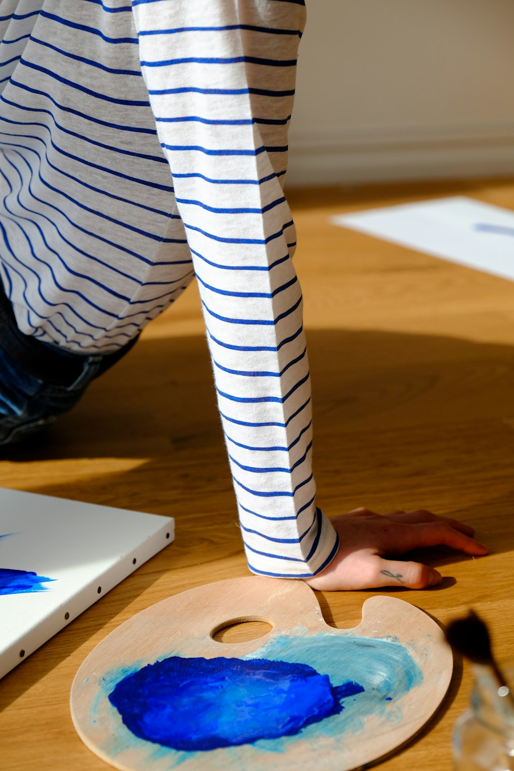 person in white and black striped long sleeve shirt sitting on brown wooden table