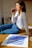 woman in white and black striped long sleeve shirt and blue denim jeans sitting on brown