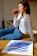 woman in white and black striped long sleeve shirt and blue denim jeans sitting on brown