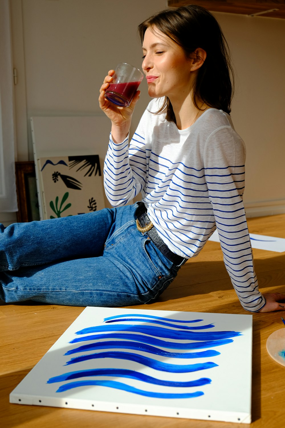 Mujer con camisa de manga larga a rayas blancas y negras y jeans de mezclilla azules sentada en marrón