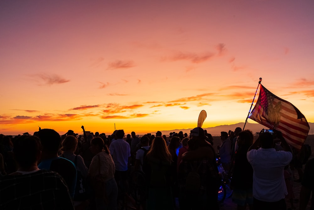 people standing on field during sunset