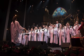 group of people in white robe standing on stage