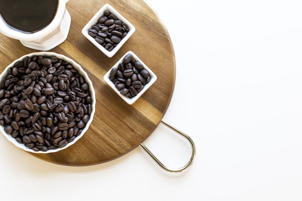 black coffee beans on brown wooden round bowl