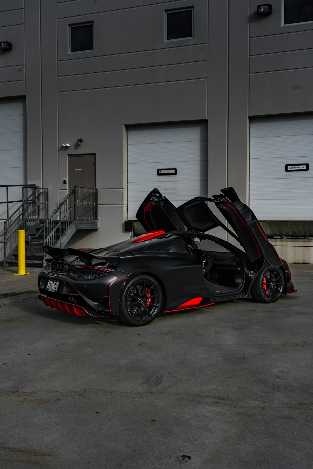 black and red sports car parked beside white garage door