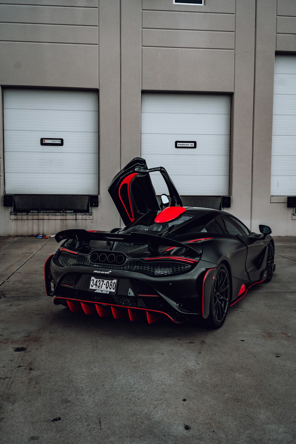 Coche deportivo Ferrari negro y rojo aparcado junto a la puerta de garaje blanca