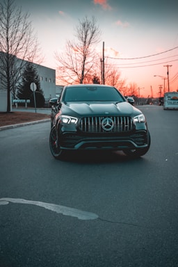 Sleek black luxury sedan parked on a city street at sunset
