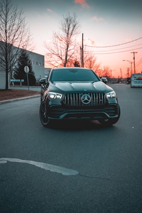 A sleek black luxury sedan parked in front of Charlotte's skyline at sunset.