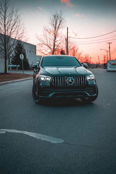 Sleek black luxury sedan parked on a city street at sunset