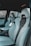 The interior of a car featuring luxury sports seats with a sleek design. The seats are predominantly light grey with black accents and have noticeable logos on the headrests. There is a spacious middle console and visible car doors showcasing a modern and upscale finish.