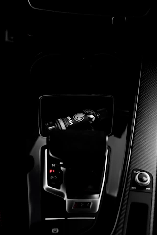 Close-up of a sleek car perfume bottle resting on a minimalist dashboard with soft natural light.