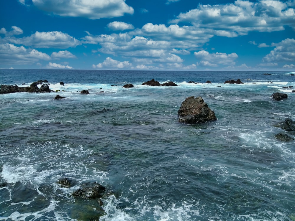 rocky shore under blue sky and white clouds during daytime