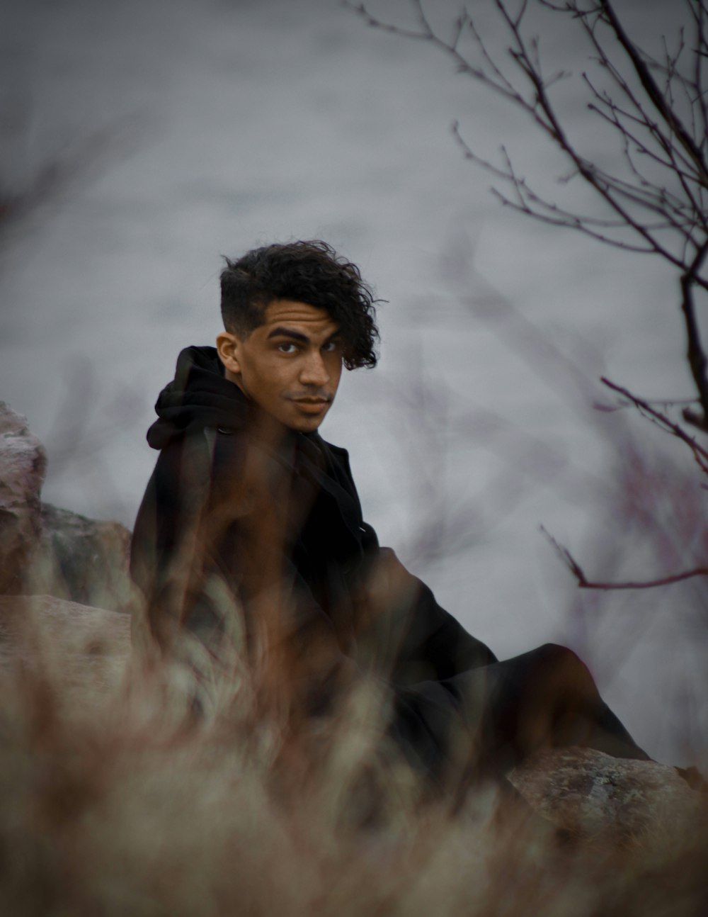 man in black jacket sitting on brown rock