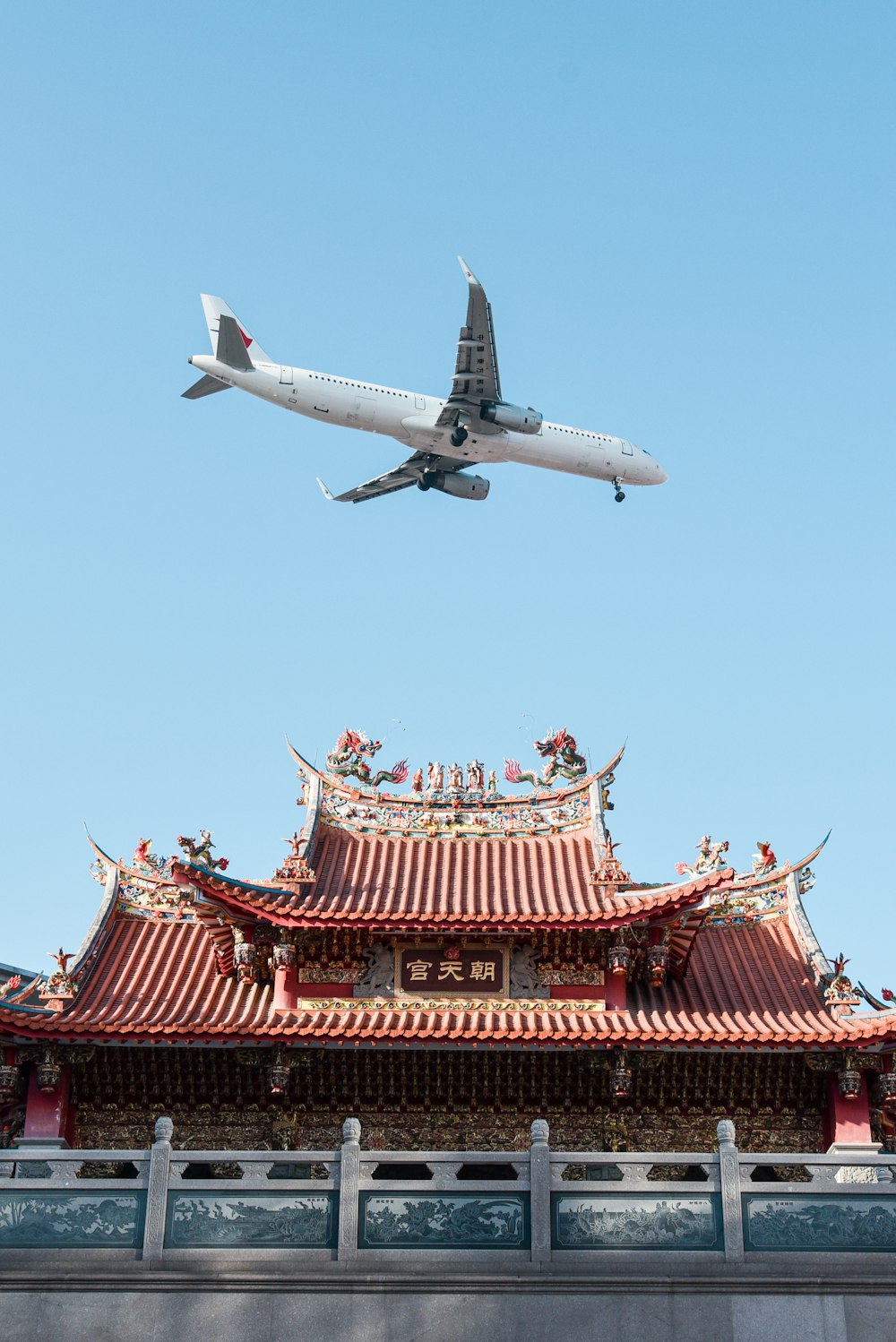 white and red passenger plane flying over red and white building during daytime