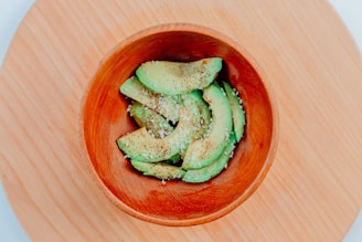 Freshly sliced avocado halves resting on a dark slate plate with a sprinkle of sea salt.