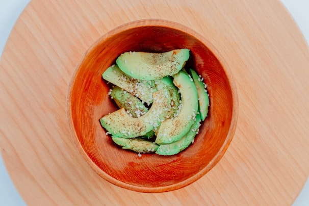 Freshly sliced avocado halves resting on a dark slate plate with a sprinkle of sea salt.