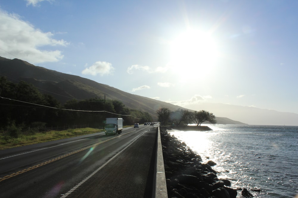 white truck on road near body of water during daytime