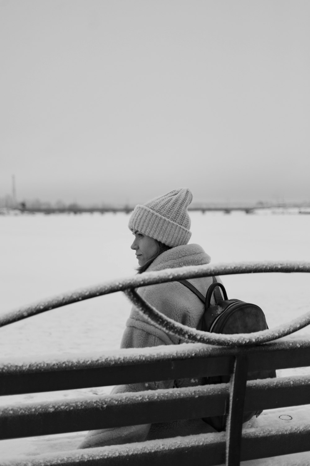 Graustufenfoto einer Frau mit Sonnenhut, die auf der Bank sitzt