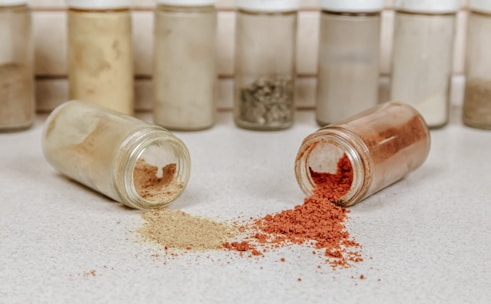 Colorful assortment of seasoning powders spilling gently onto a kitchen counter