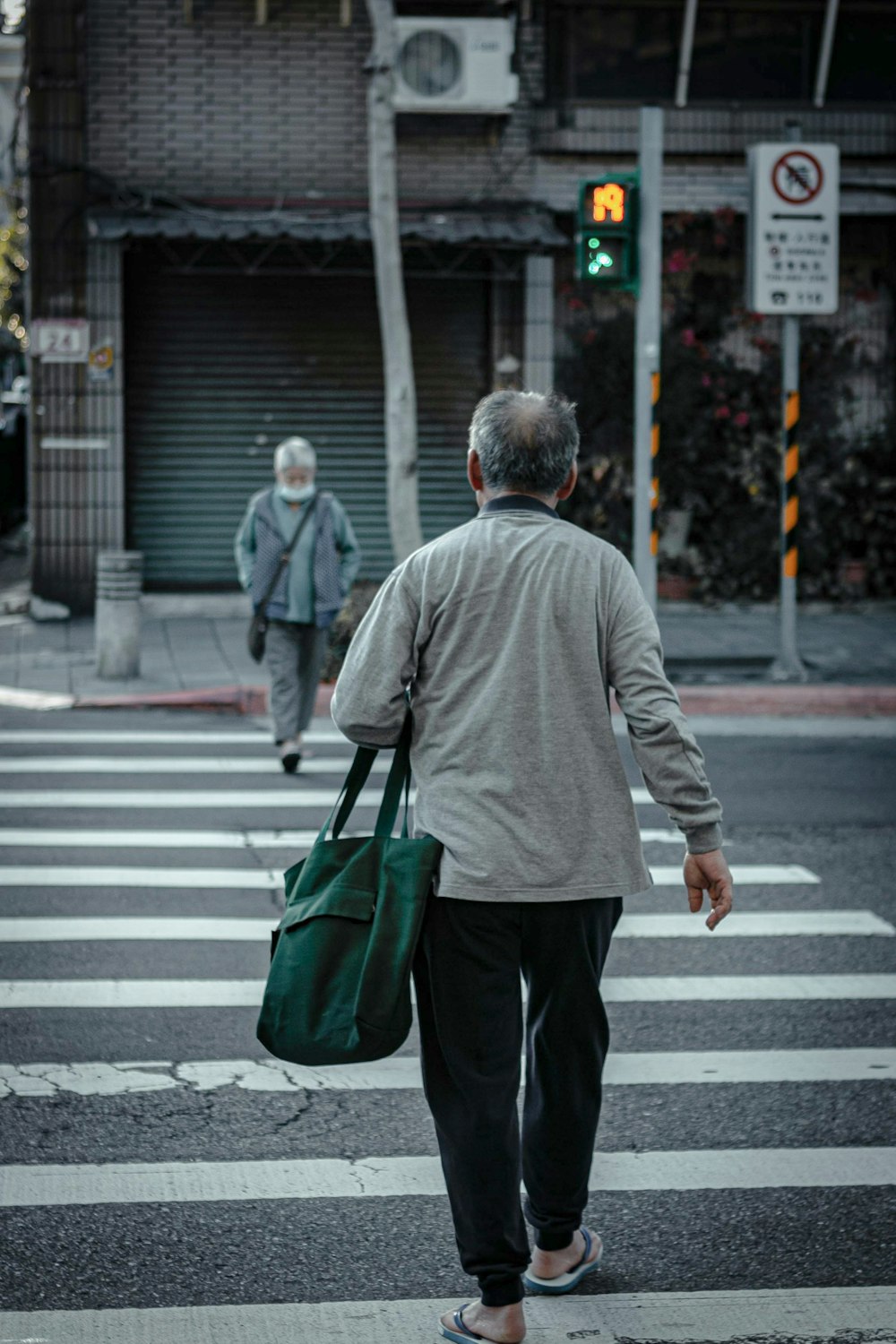 man in gray hoodie walking on pedestrian lane during daytime