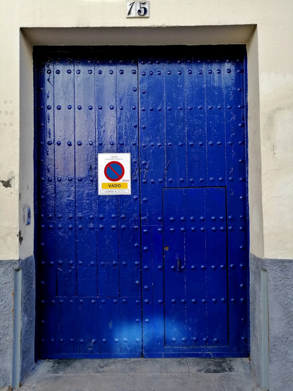 Puerta de metal azul con pegatina blanca y roja