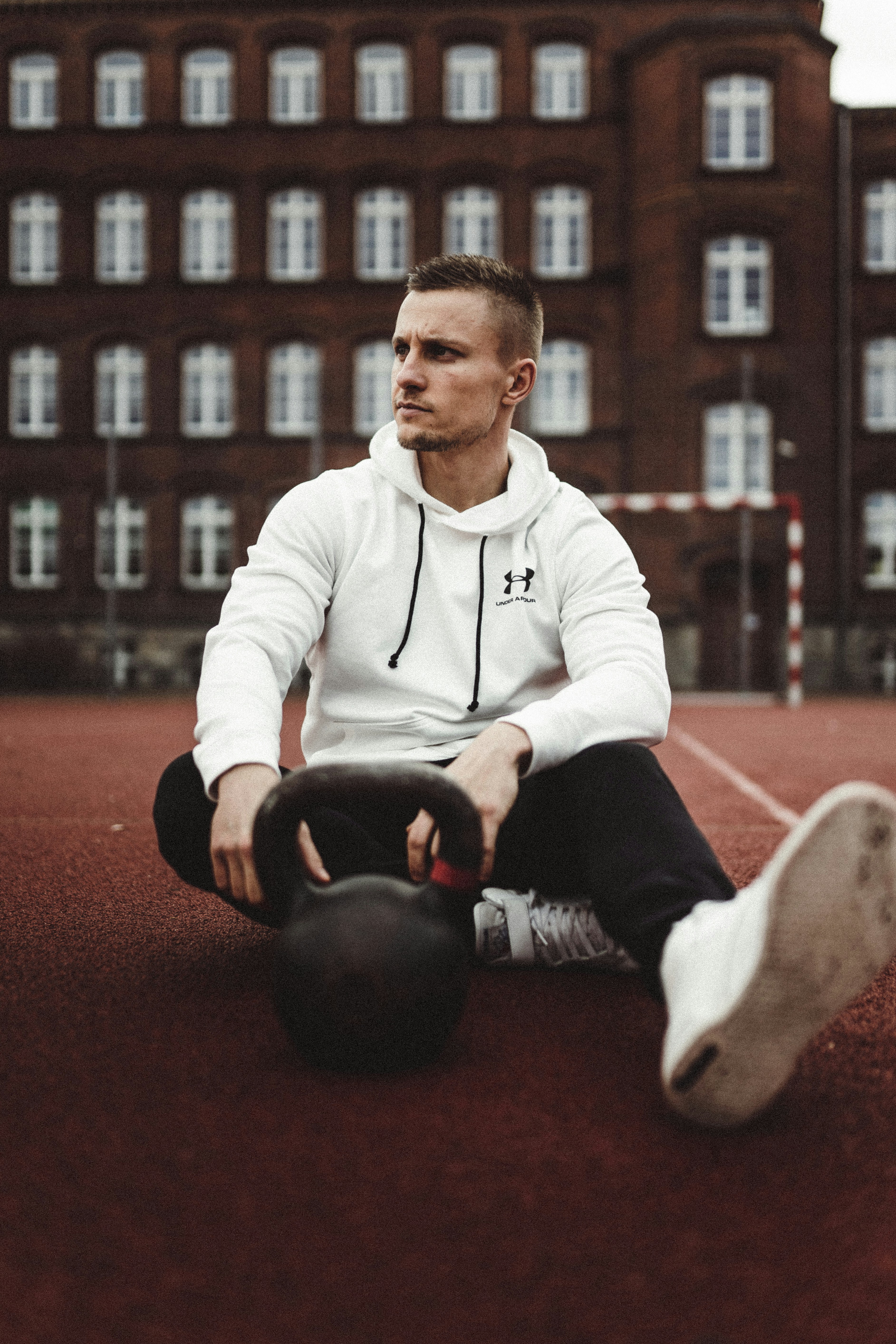 Mann in weißer Nike-Reißverschlussjacke und schwarzer Hose auf rotem Teppich