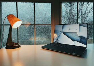 A cozy scene of a student working on a tablet by a window with snow outside.