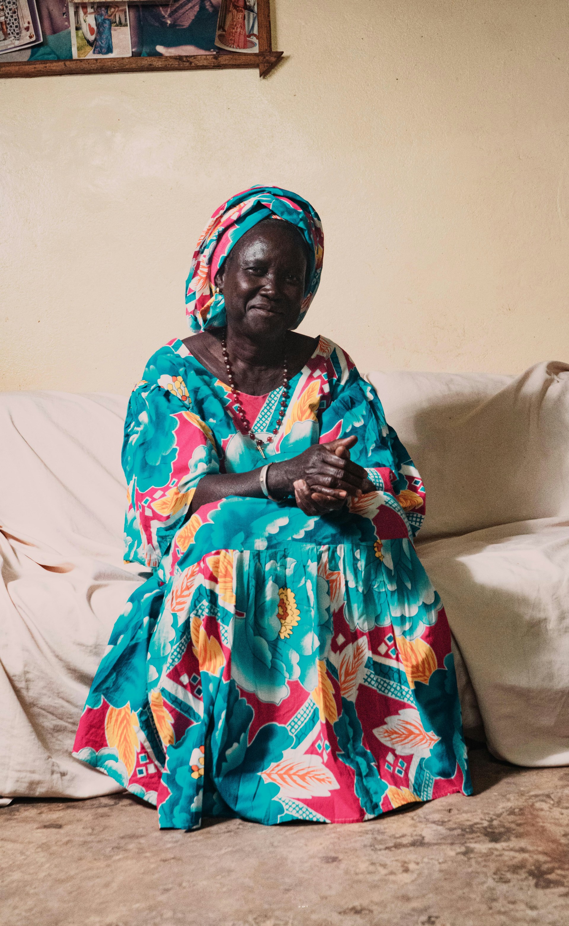 woman in blue red and yellow floral dress sitting on white bed