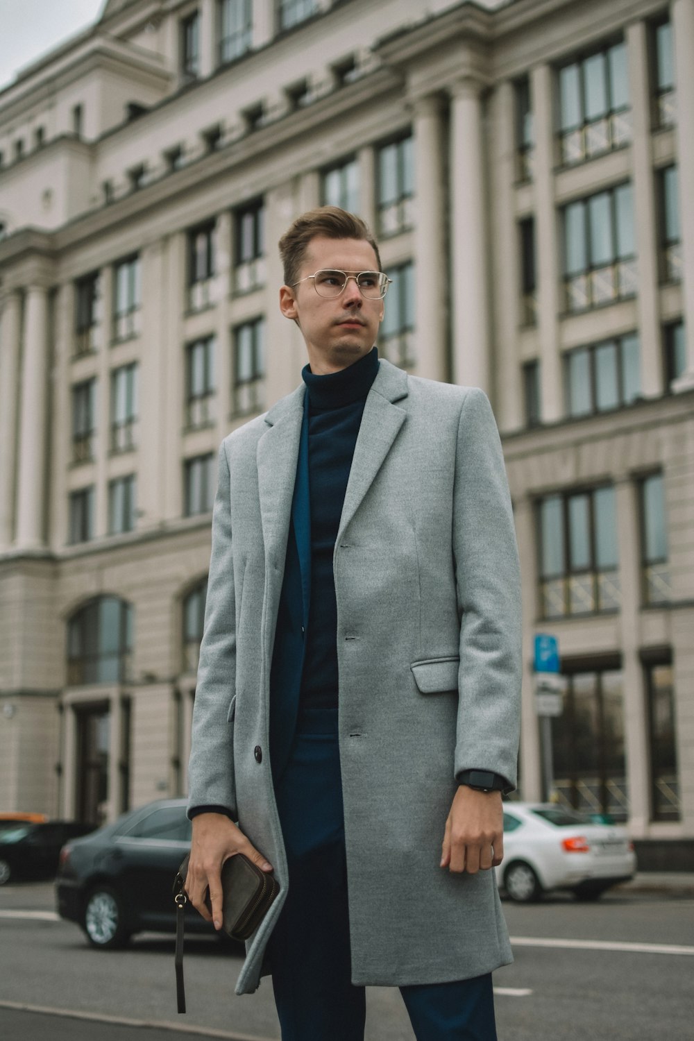 man in gray suit jacket standing near cars during daytime