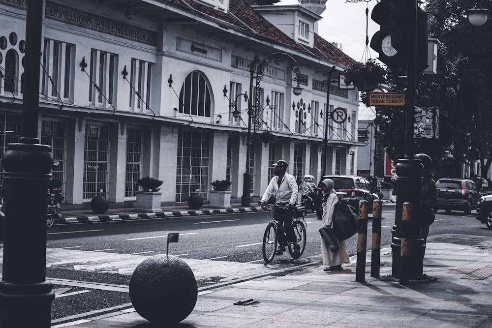 people riding bicycles on road near white concrete building during daytime