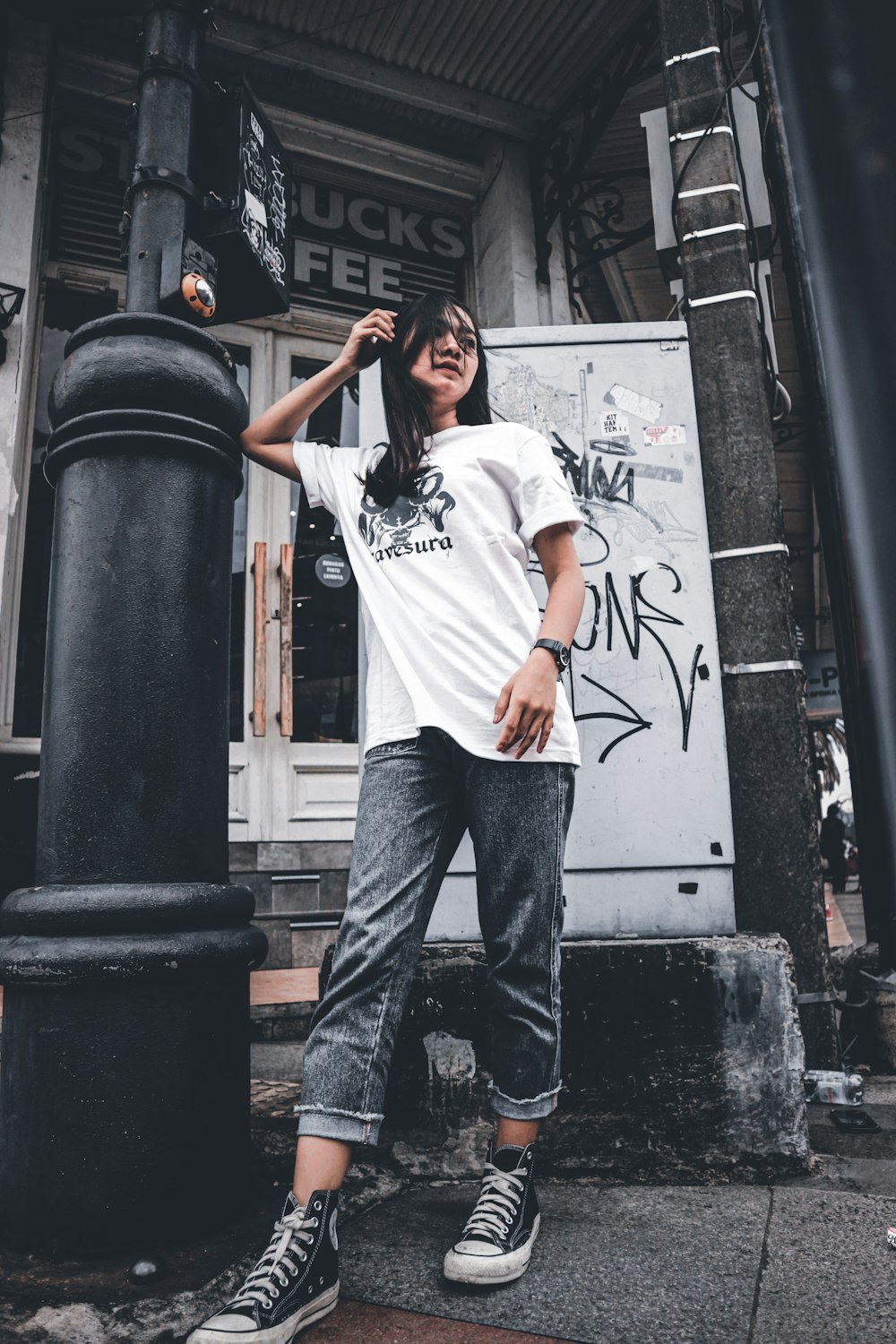 man in white crew neck t-shirt and blue denim jeans standing beside black steel post