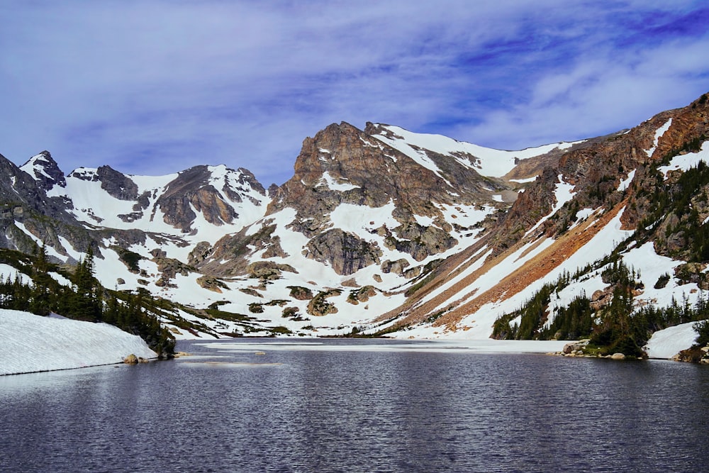 snow covered mountain near body of water during daytime