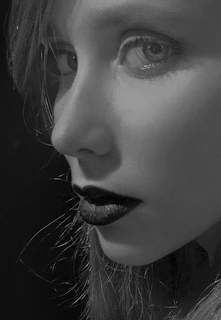 A stylish model wearing bold eyeliner and matte lipstick in monochrome tones.