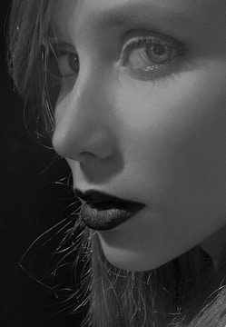 Portrait of a model with striking smoky eyes and deep red lips under warm lighting.