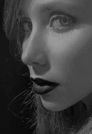 A stylish model wearing bold eyeliner and matte lipstick in monochrome tones.