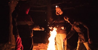 A group of people learning survival skills around a campfire in a forest.