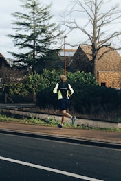 man in black shirt and white shorts running on road during daytime