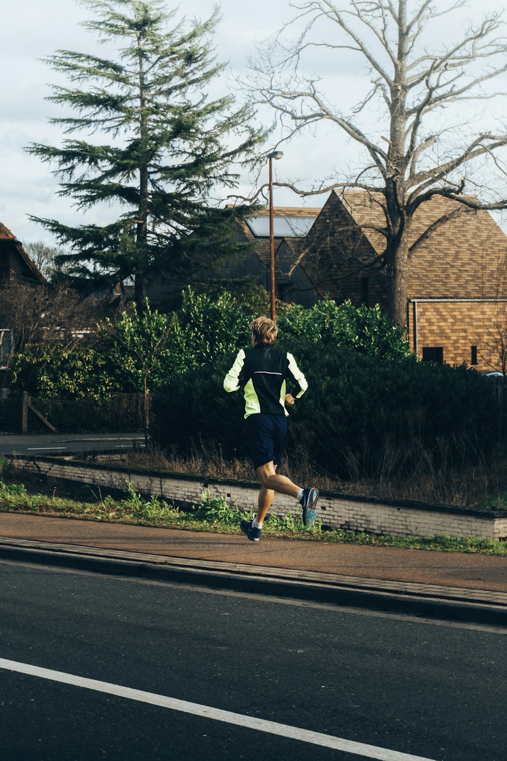 man in black shirt and white shorts running on road during daytime