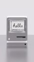 Miniaturní staromódní iMac s nápisem 'hello' na obrazovce.