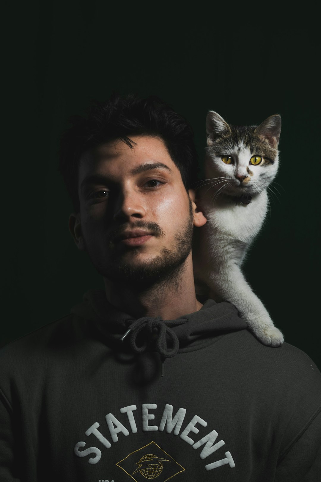 man in black crew neck shirt holding white and gray cat