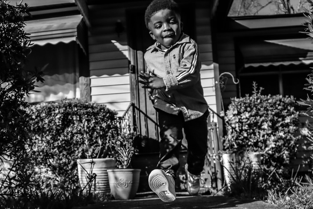 grayscale photo of boy in hoodie and pants playing basketball