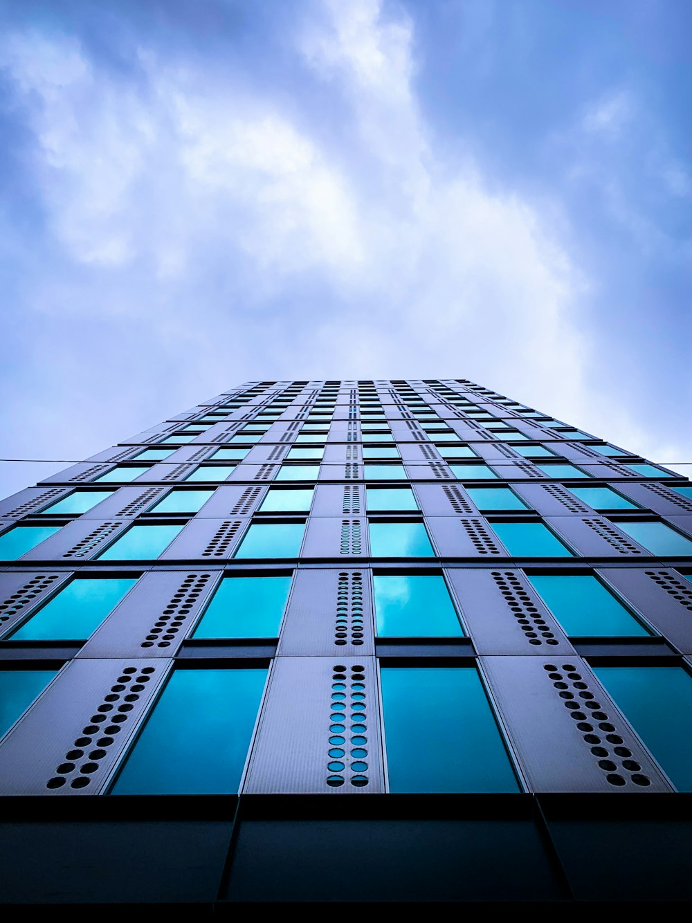 white clouds over blue glass building