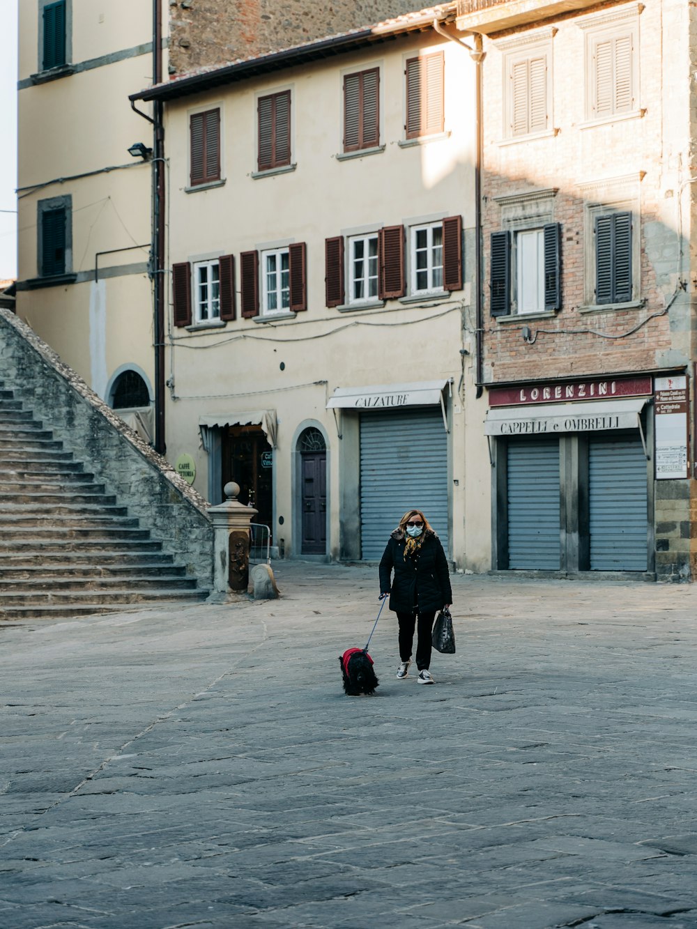 woman in black coat walking on sidewalk during daytime