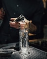 person pouring water on clear drinking glass