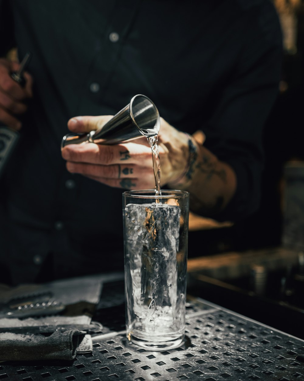 personne versant de l’eau sur un verre à boire transparent