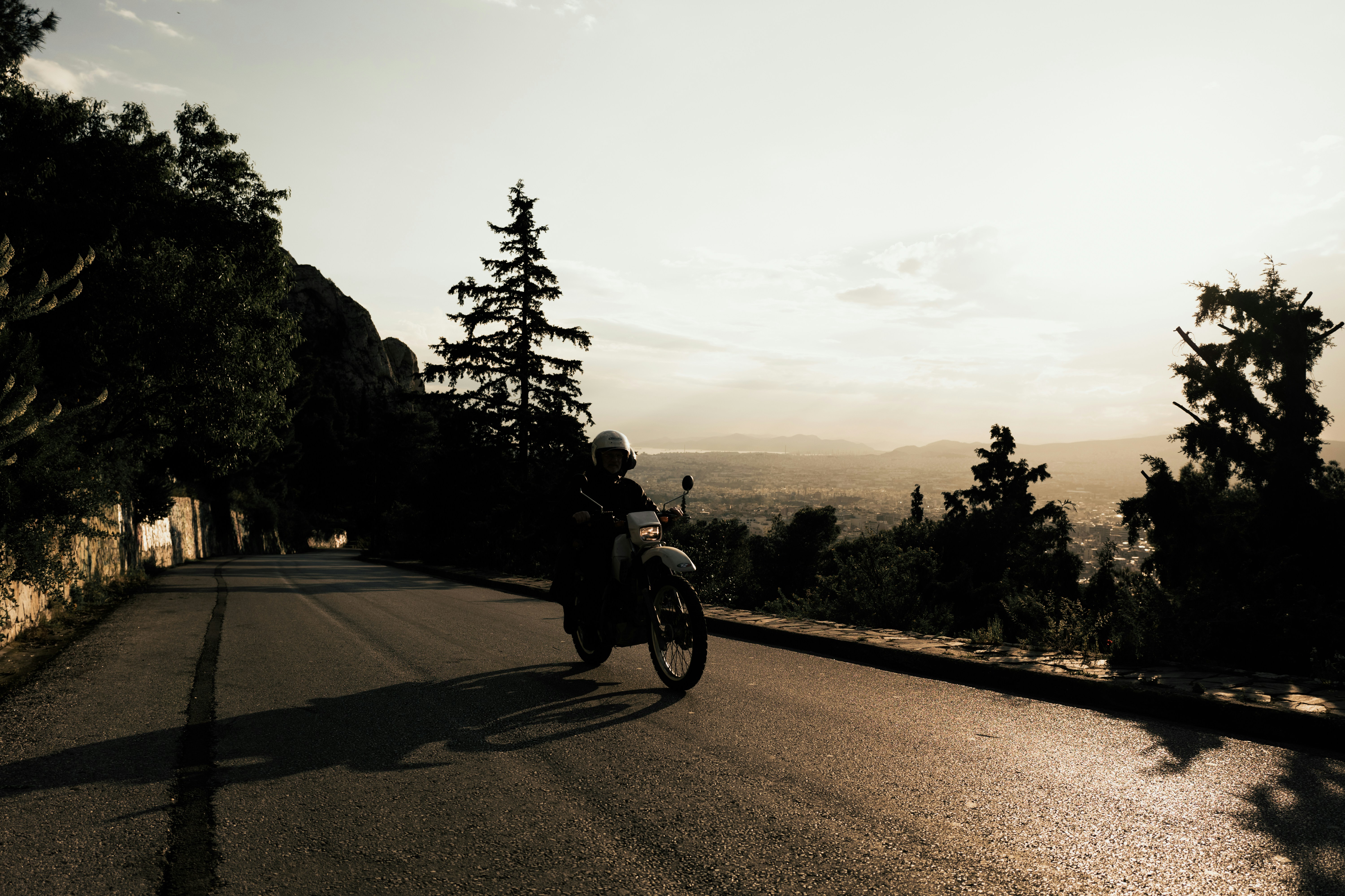 grayscale photo of man riding motorcycle on road