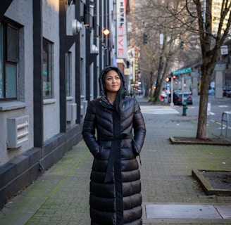 woman in black bubble jacket standing on sidewalk during daytime