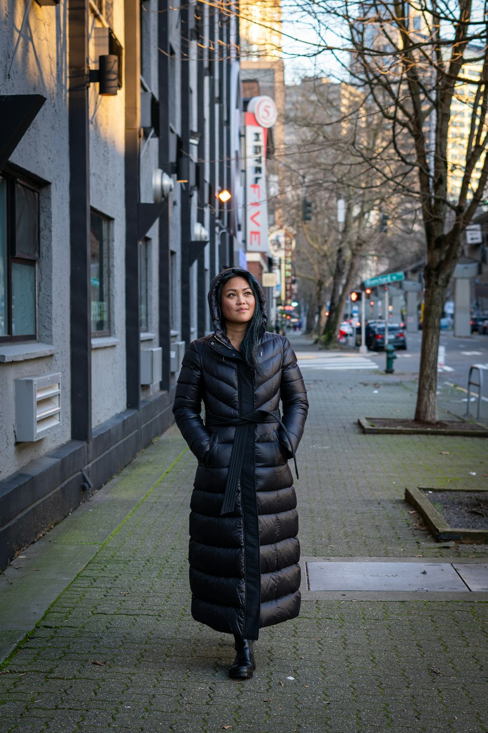 femme en veste à bulles noire debout sur le trottoir pendant la journée