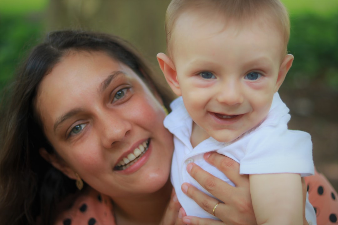 smiling woman holding baby in white shirt